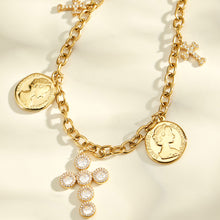 Close-up of a gold-tone cross necklace with two coin pendants and small side charms