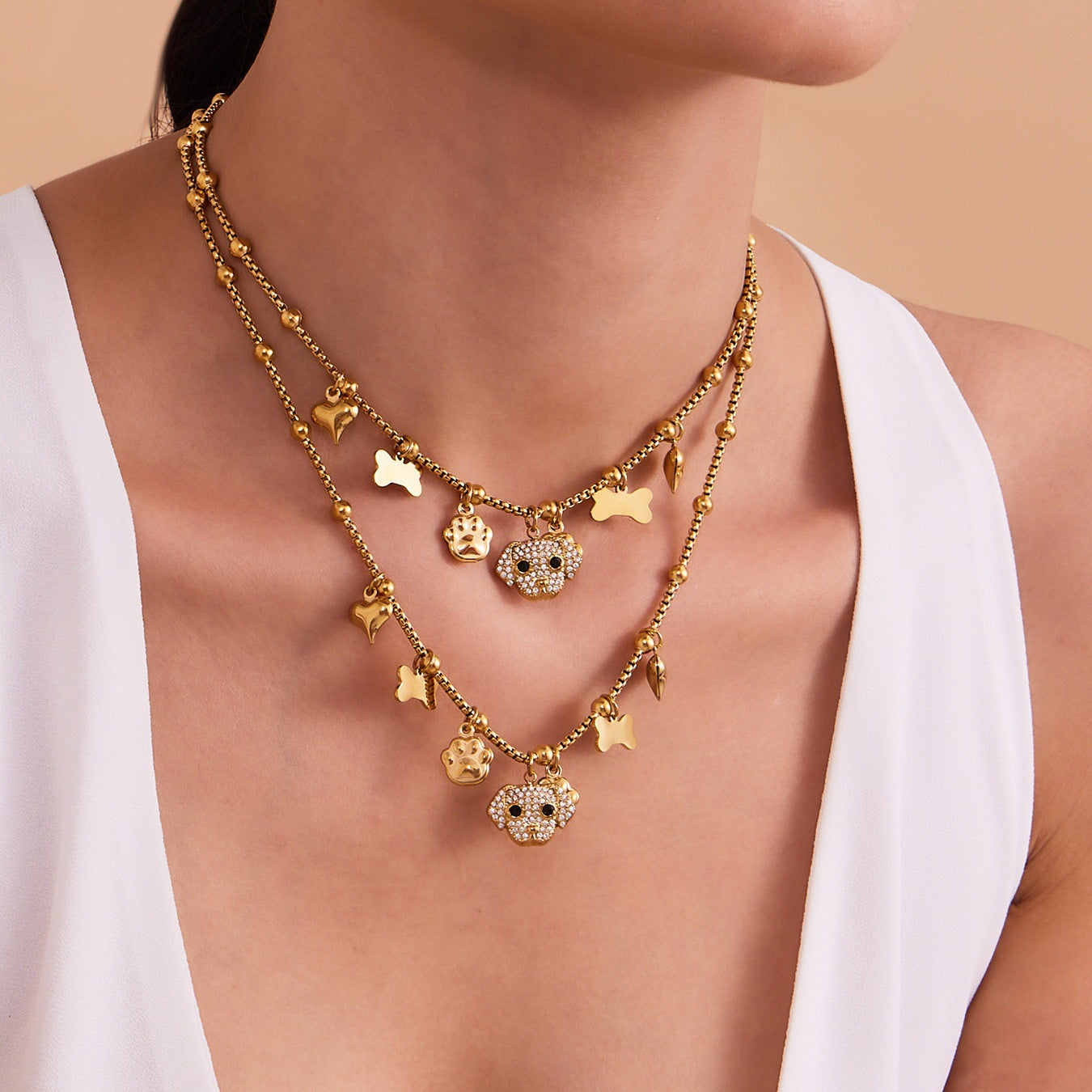 A woman wearing layered hypoallergenic dog and bone pendant necklaces with sparkling zircon on sensitive skin.