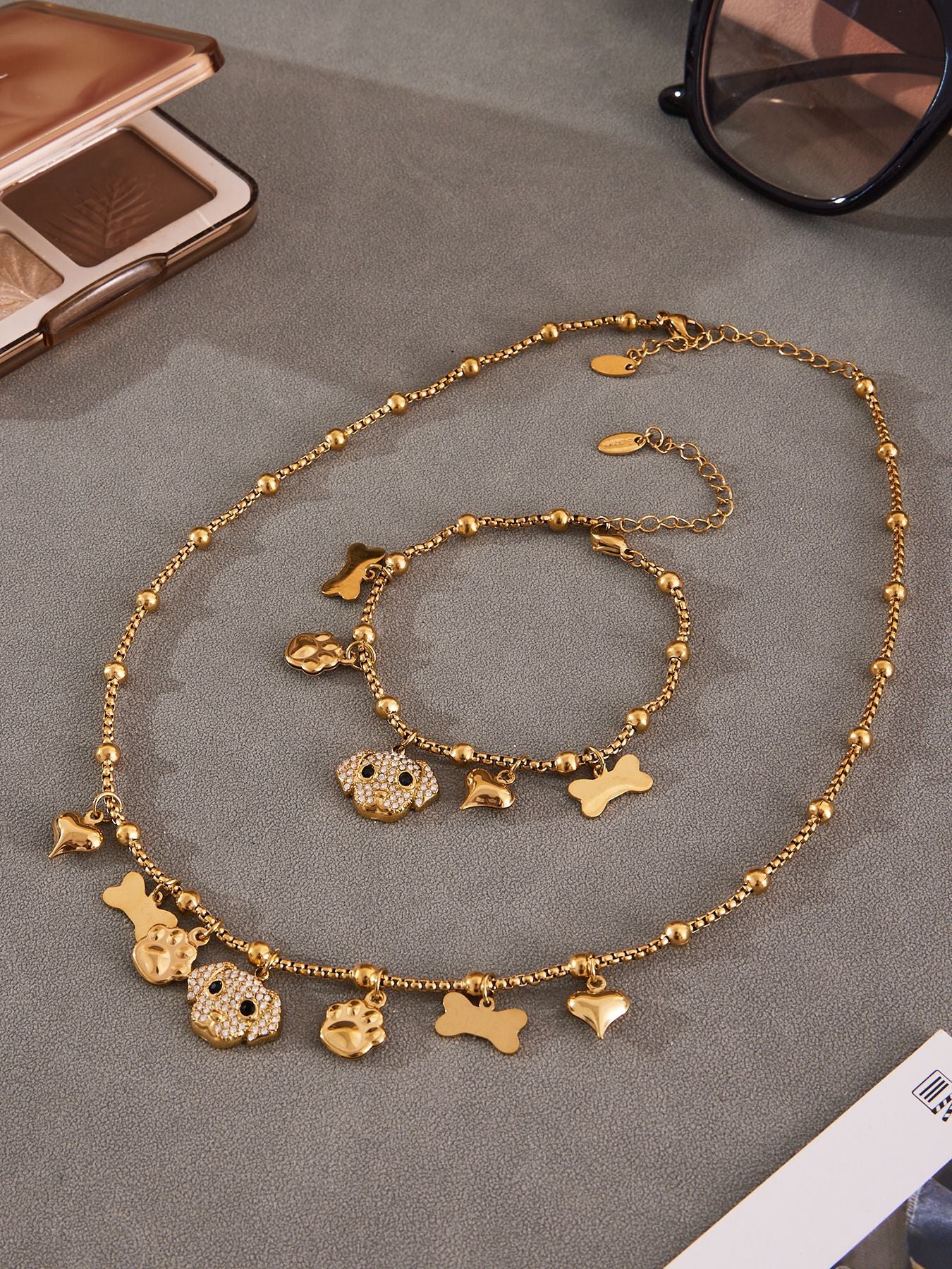 Gold and silver tone dog charm rings and bracelets displayed together, 316L stainless steel hypoallergenic jewelry.