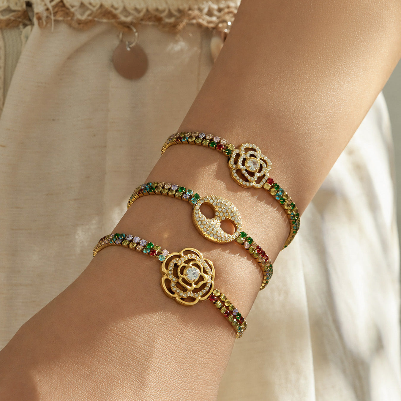 Three multicolor zircon bracelets in gold finish layered on the wrist