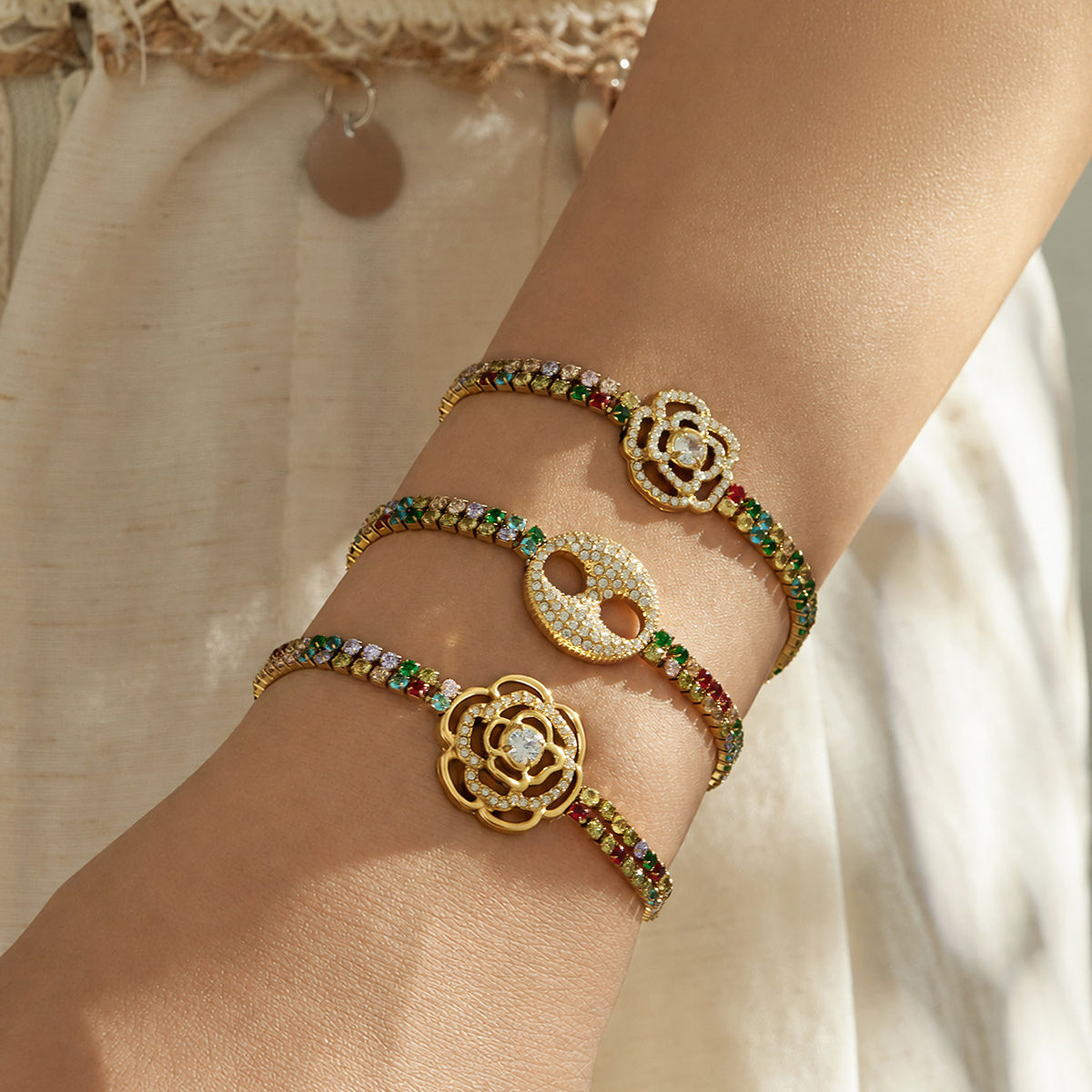 Three multicolor zircon bracelets in gold finish layered on the wrist