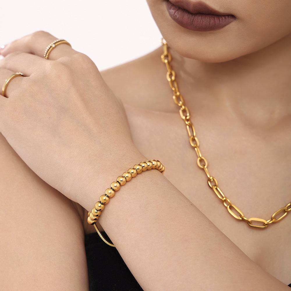 Gold bead slider bracelet made of 316L stainless steel worn as minimalist stacking jewelry