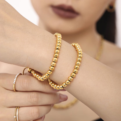 Close-up of gold bead slider bracelet in 316L stainless steel stacked with other bracelets