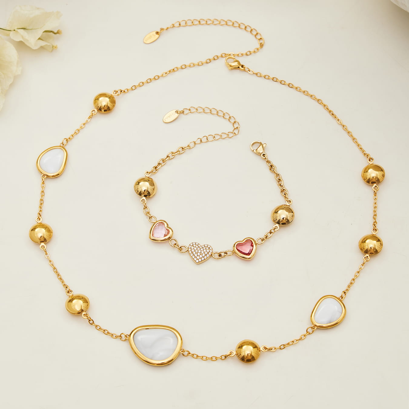 Flat lay of 316L stainless steel heart glass stone jewelry set in gold white and pink tones