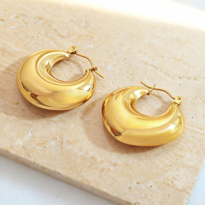 Flat lay of steel heart huggie hoop earrings made from 316L stainless steel