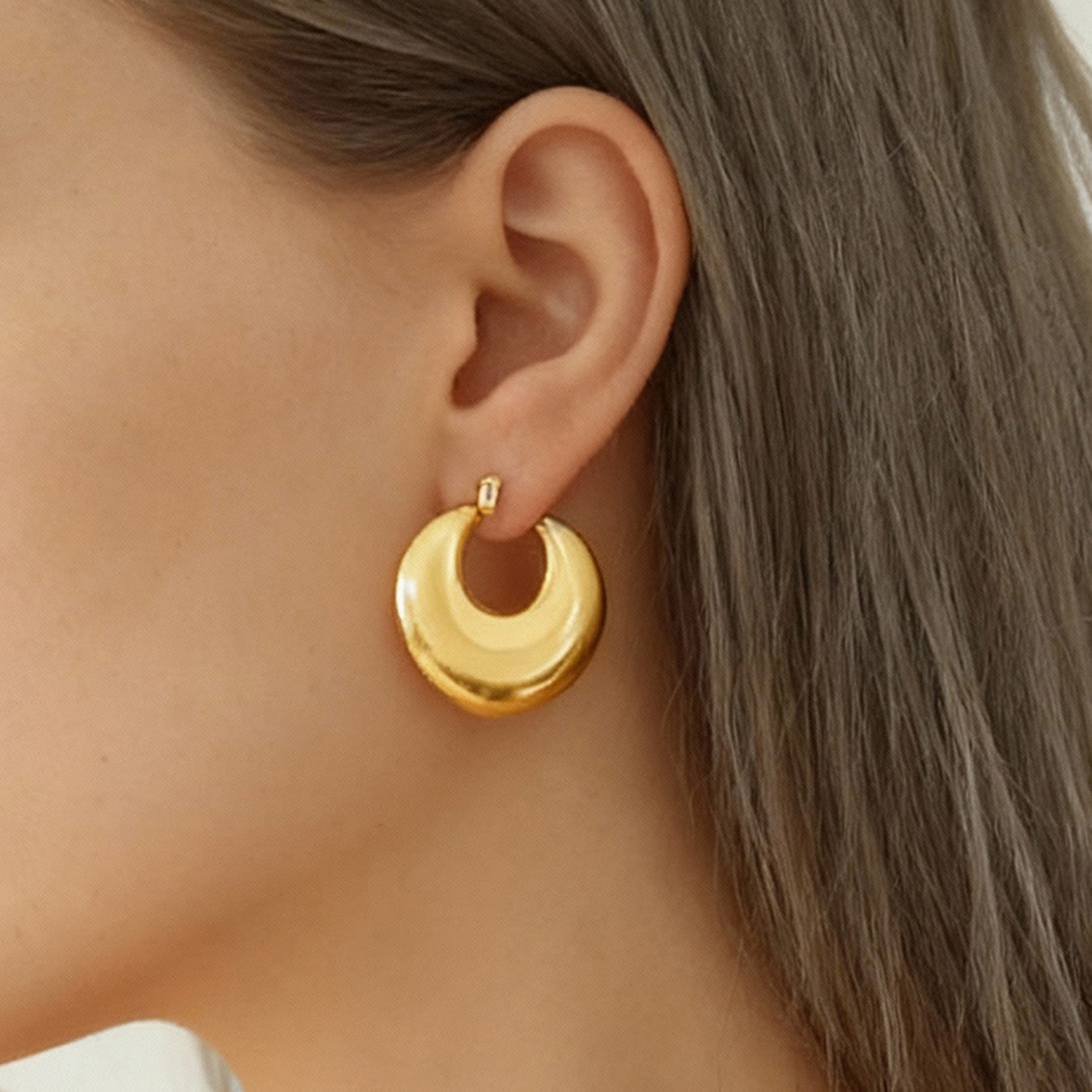 Model wearing gold 316L stainless steel heart huggie hoop earrings close up