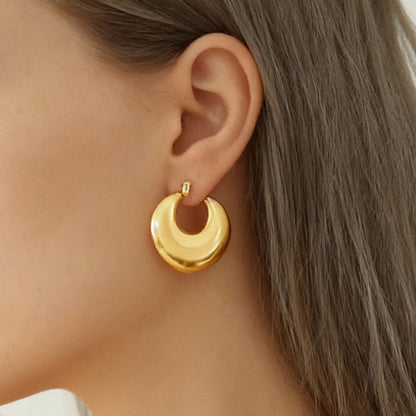 Model wearing gold 316L stainless steel heart huggie hoop earrings close up