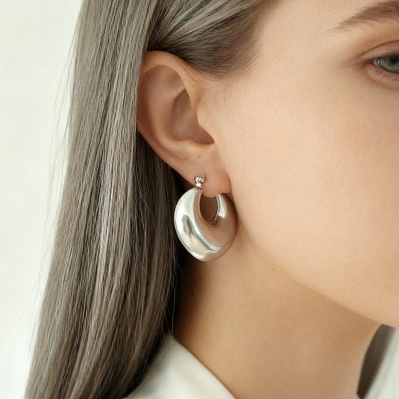 Model wearing steel tone 316L stainless steel heart huggie hoop earrings