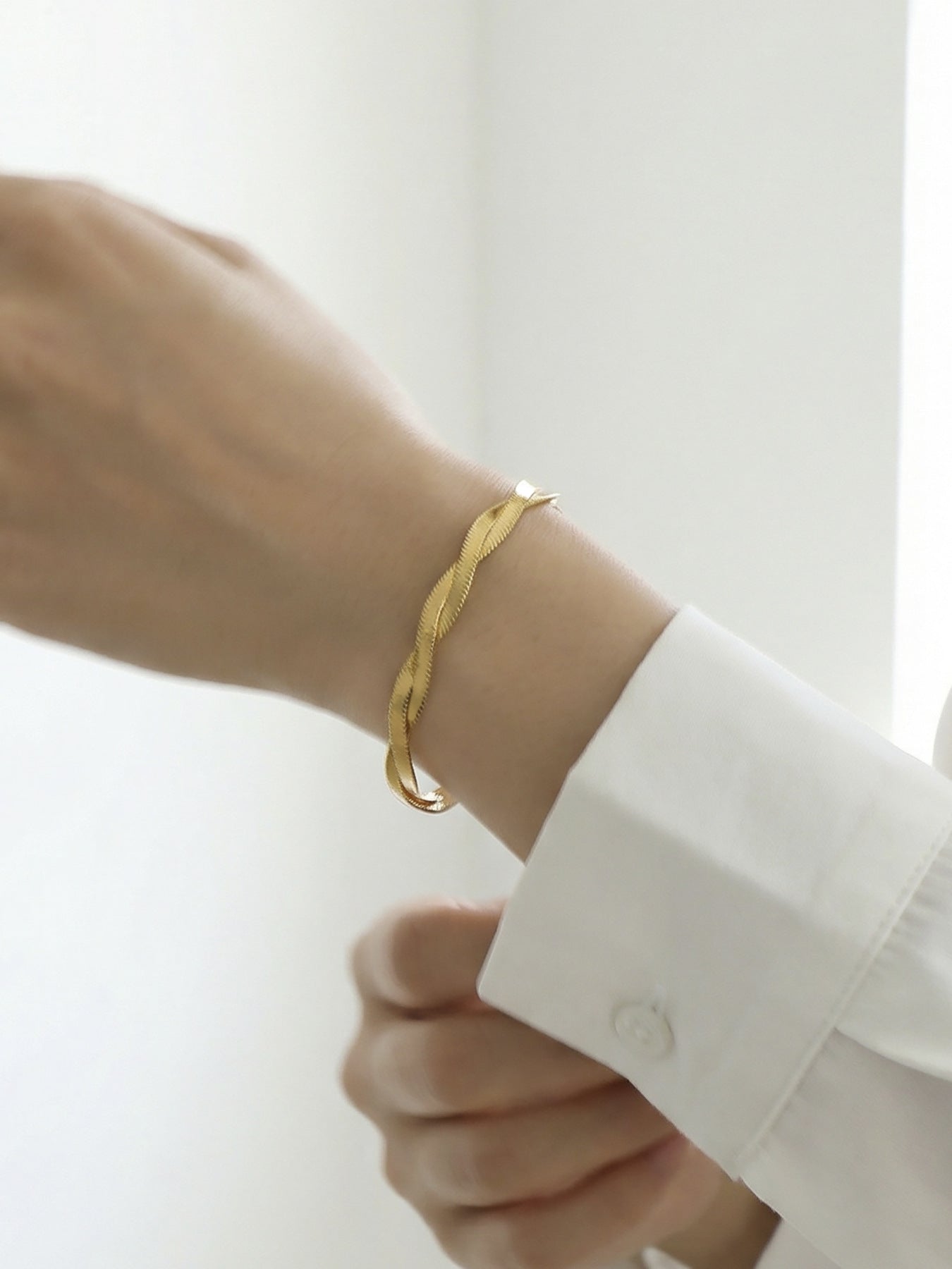 Model wearing 316L Stainless Steel minimalist intertwined blade chain bracelet, 18K gold PVD finish, hypoallergenic