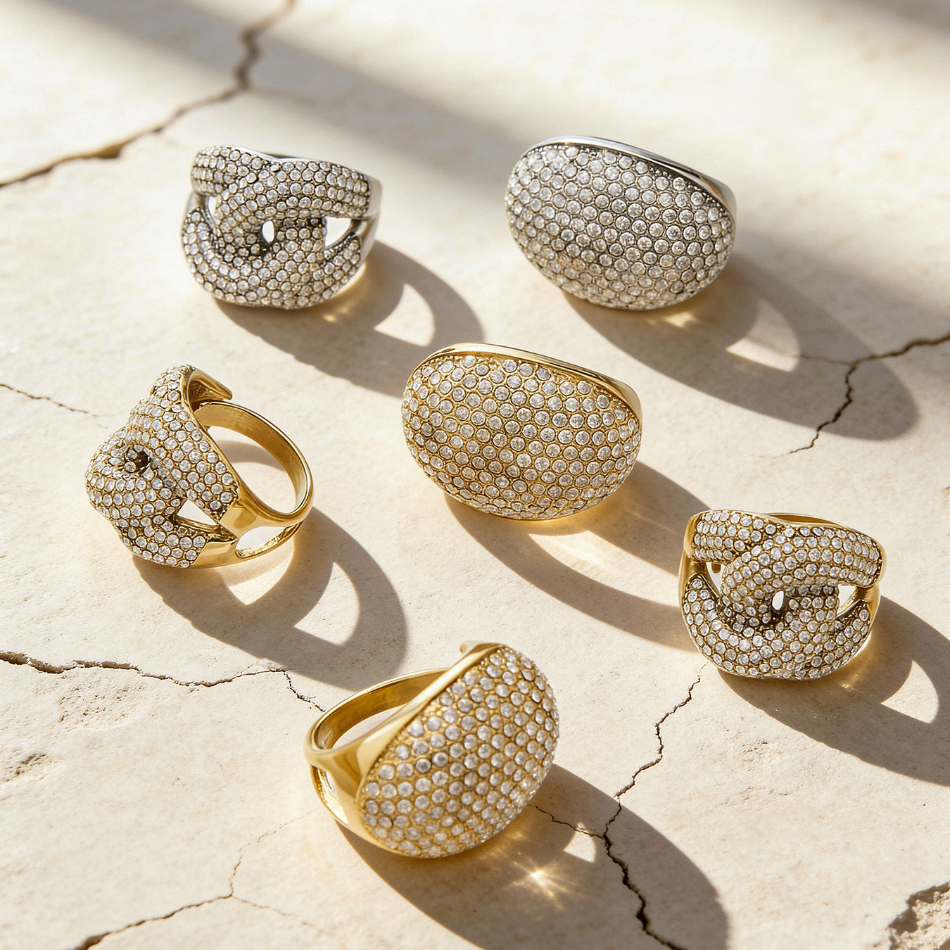 Flat lay of 316L stainless steel pavé zircon rings in gold and steel tones for wholesale assortment preview