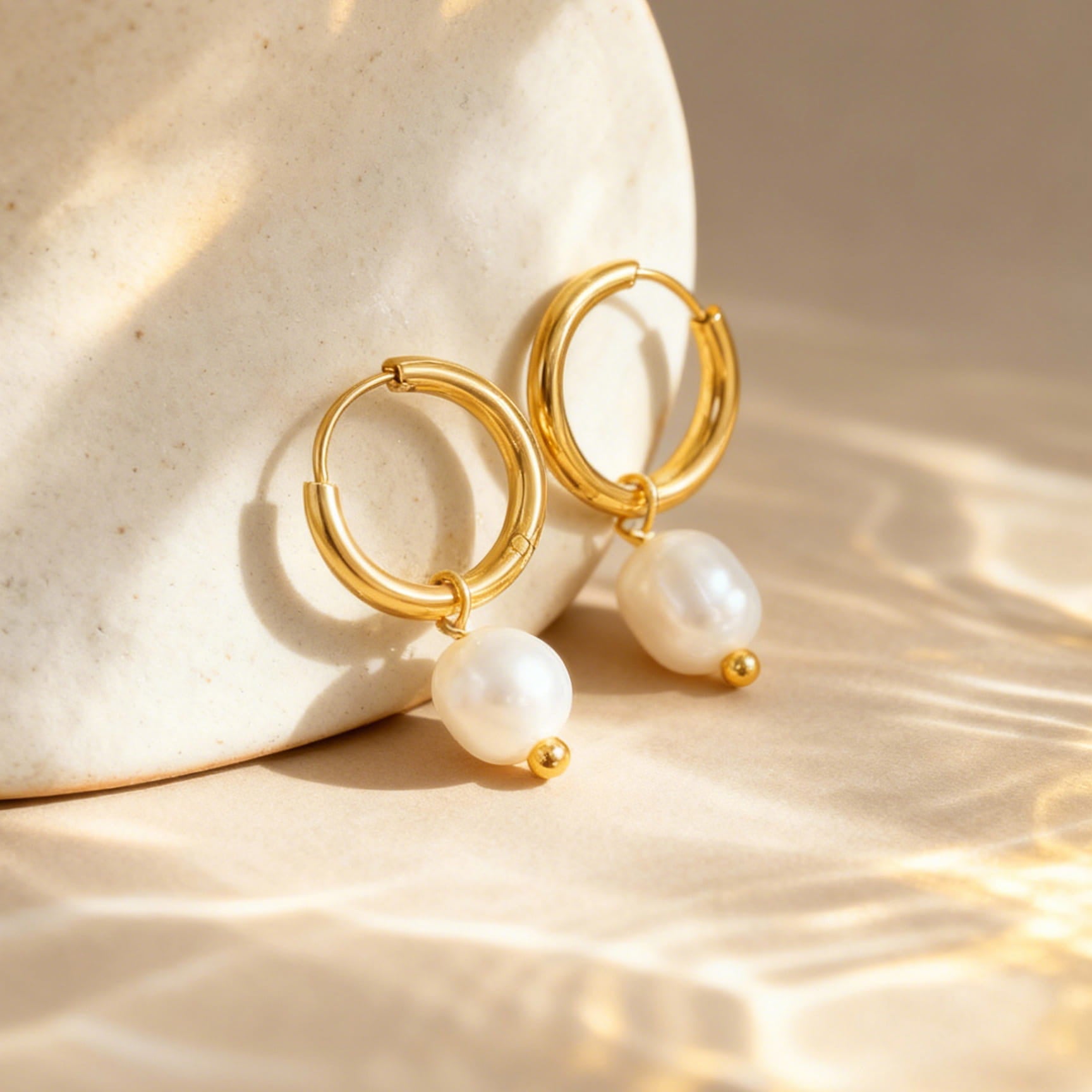 Flat lay of 316L stainless steel freshwater pearl hoop earrings 18K PVD gold plated minimalist boutique wholesale jewelry