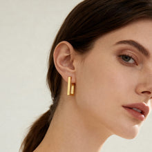 316L stainless steel rectangular huggie hoop earrings worn on ear close up gold tone