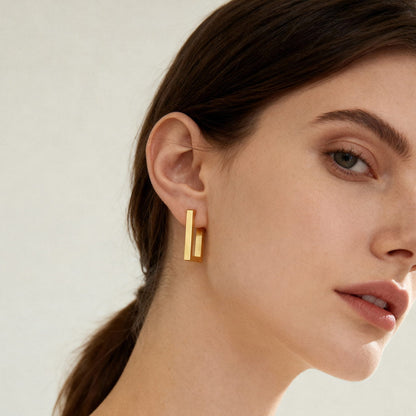 316L stainless steel rectangular huggie hoop earrings worn on ear close up gold tone