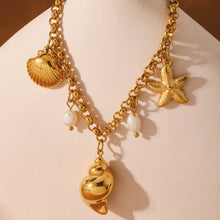 Close-up of gold conch shell freshwater pearl and starfish charm anklet on warm towel, waterproof stainless steel beach jewelry