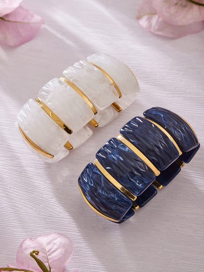 White and navy textured resin wide bracelets with gold stainless steel links flat lay