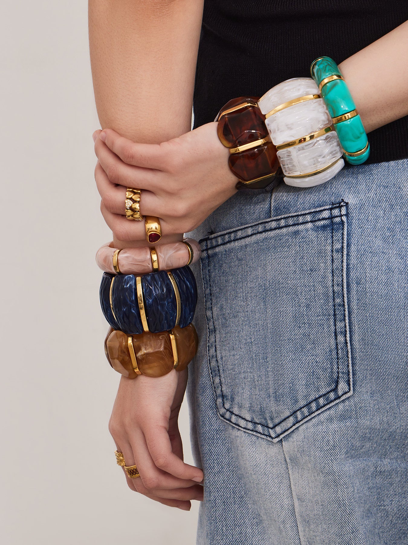 Fashion model styling multiple wide resin stretch bracelets with gold stainless steel accents