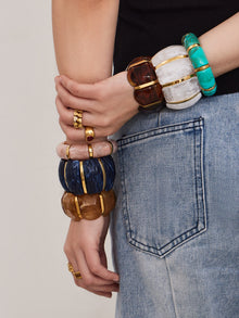 Fashion model styling multiple wide resin stretch bracelets with gold stainless steel accents