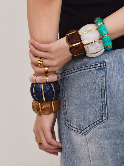 Fashion model styling multiple wide resin stretch bracelets with gold stainless steel accents