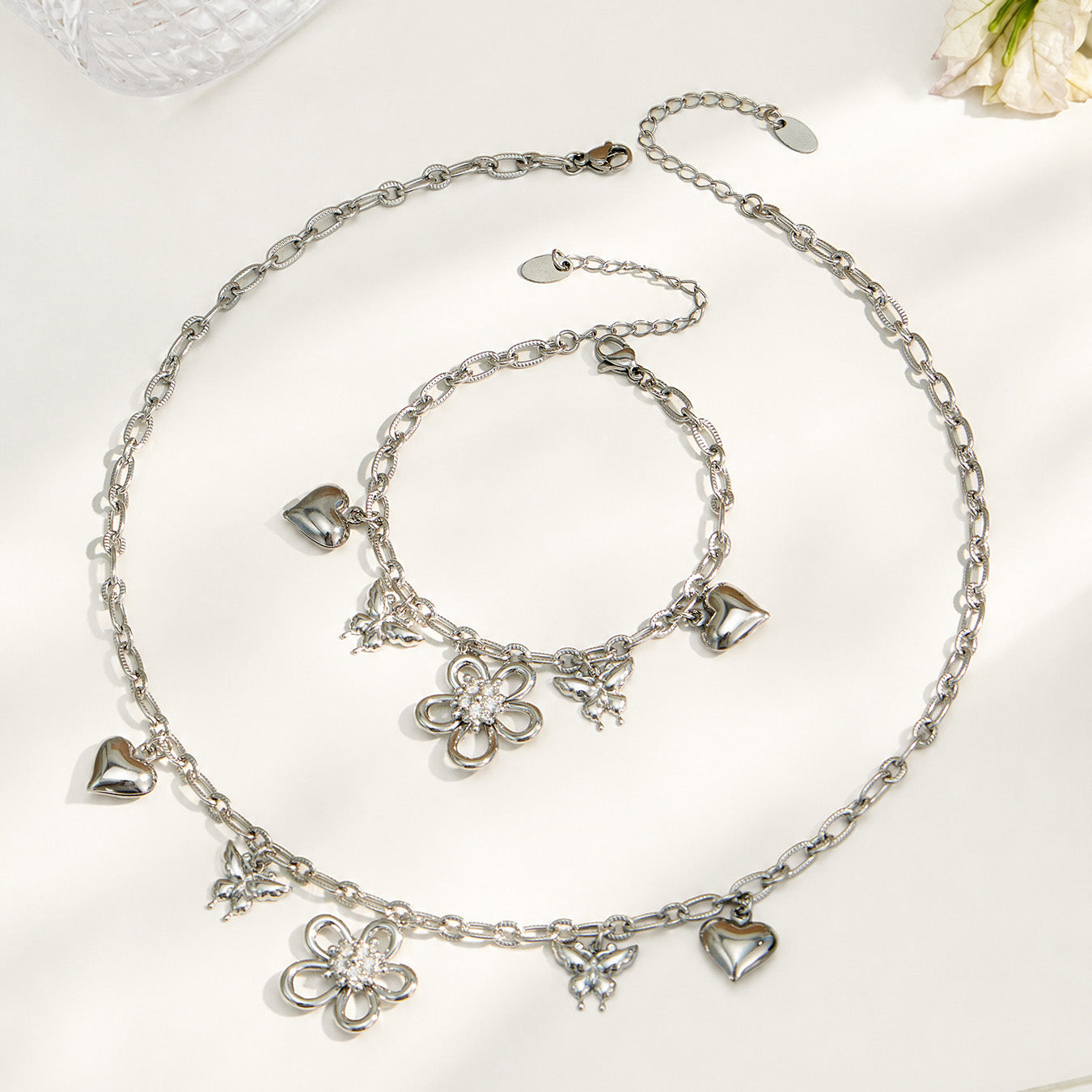 316L stainless steel butterfly charm necklace and matching floral bracelet in a polished steel finish