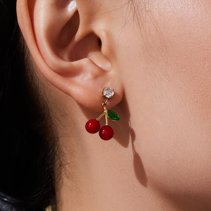 Closeup of 18k gold plated enamel red cherry earrings on ear: zircon accent