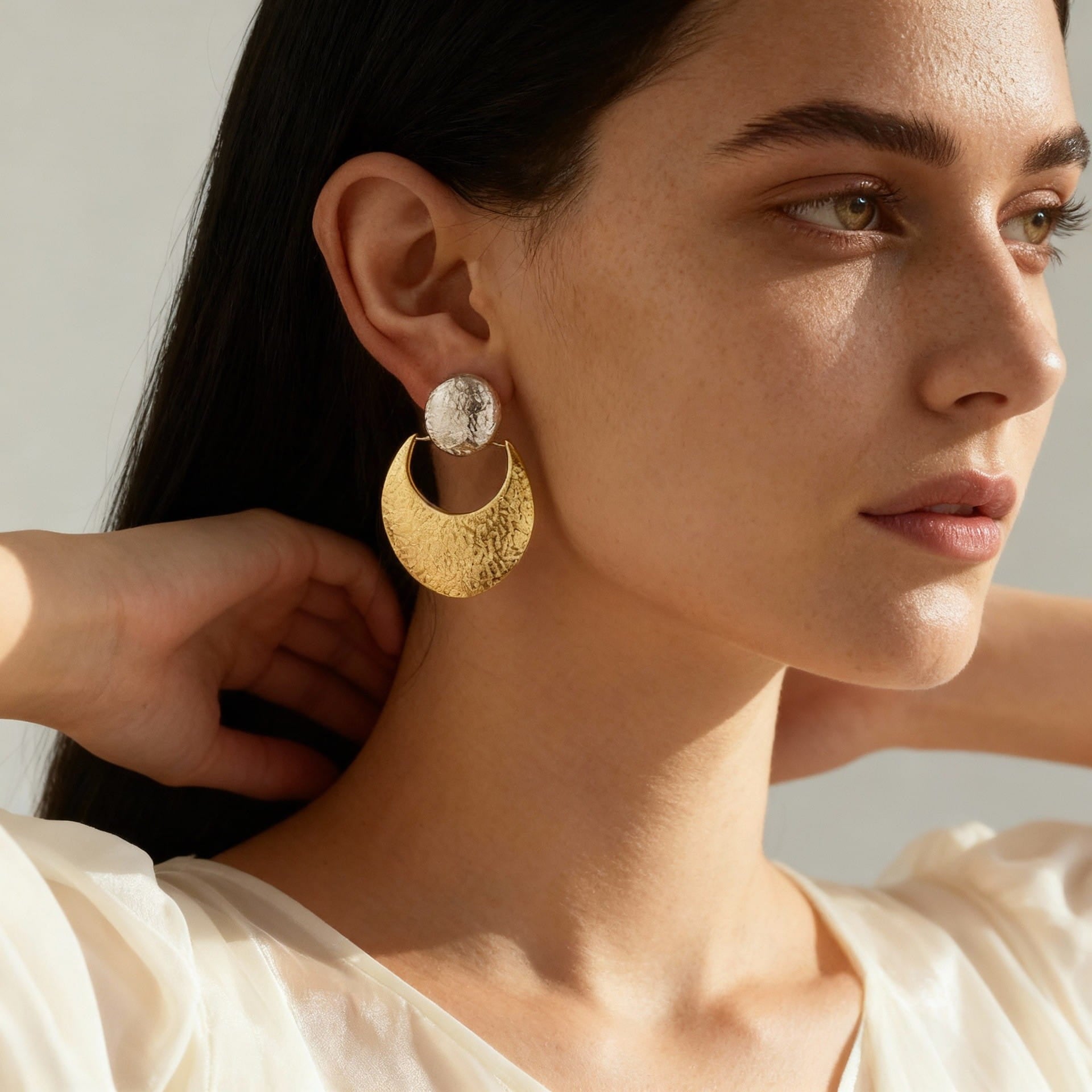 Side profile of a model wearing chunky waterproof 18K gold plated hammered crescent drop earrings.