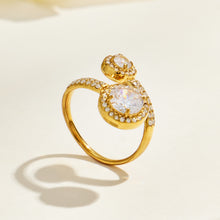 Gold-tone stainless steel double halo ring standing upright on a cream surface and casting a curved shadow