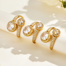 Three gold-tone stainless steel double halo rings arranged on a cream surface with the round stone settings facing forward