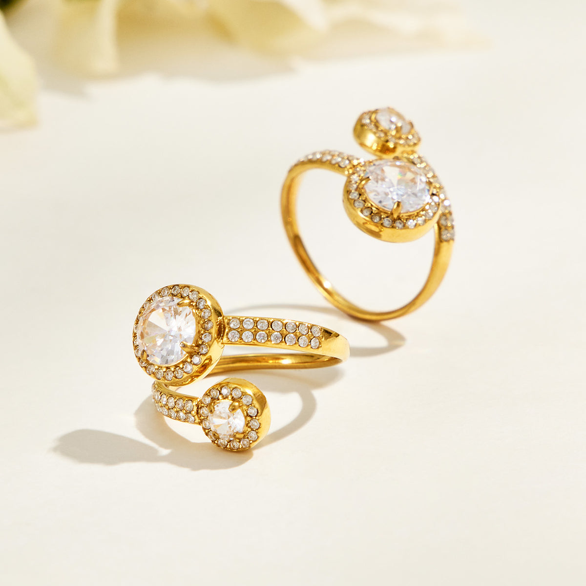 Two gold-tone stainless steel double halo rings displayed upright and tilted to show the stones and band details