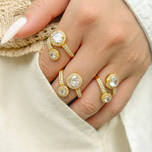 Gold-tone stainless steel double halo rings worn on a hand against white clothing
