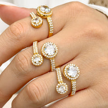 Three gold-tone stainless steel double halo rings worn on fingers, showing the large and small round stones