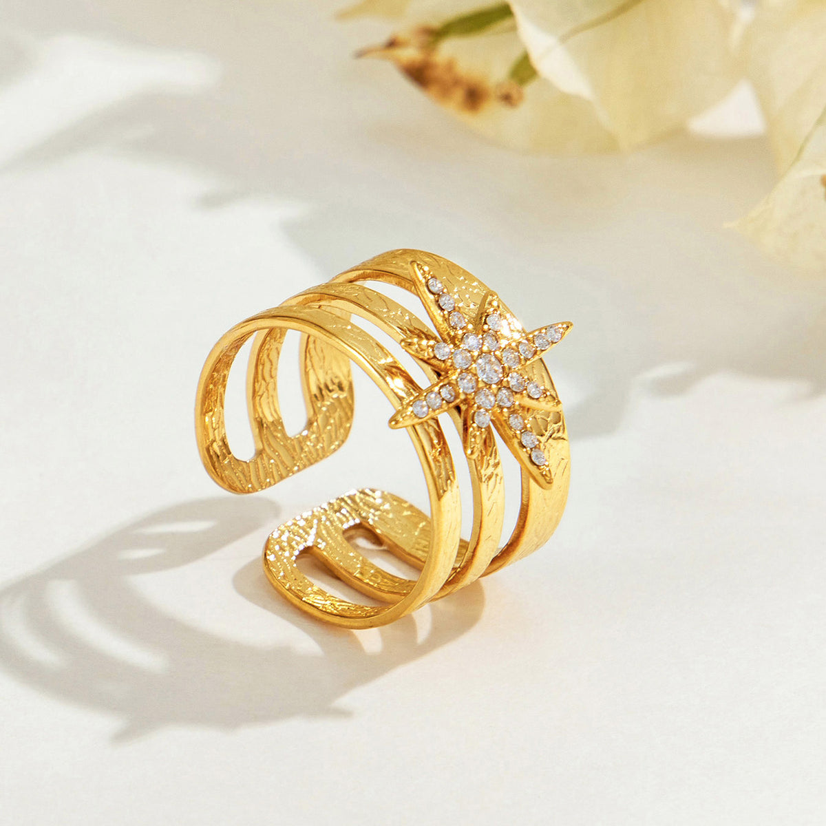 Angled view of the A194 gold-tone stainless steel starburst ring showing its stone-set motif and open band