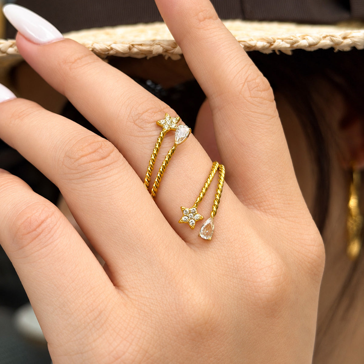 Gold-tone stainless steel twisted open rings worn on fingers, highlighting the star accents and textured bands