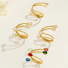 Overhead arrangement of gold-tone stainless steel twisted open rings, showing the open bands and different stone designs