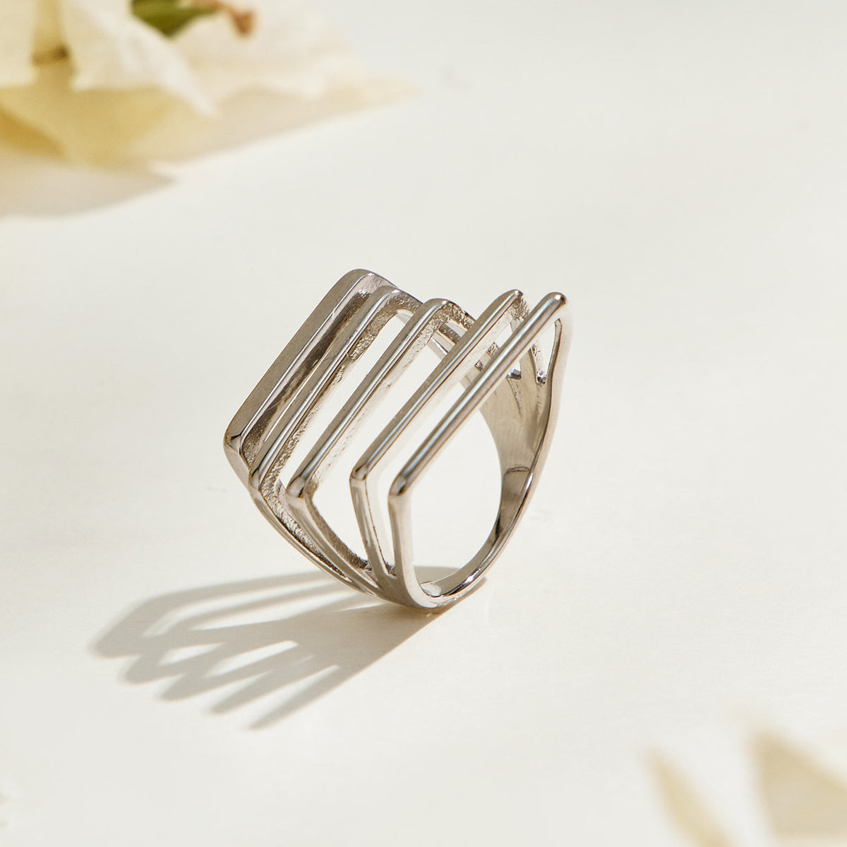 Steel-tone stainless steel multi-row ring standing at an angle, showing the geometric bars and curved band