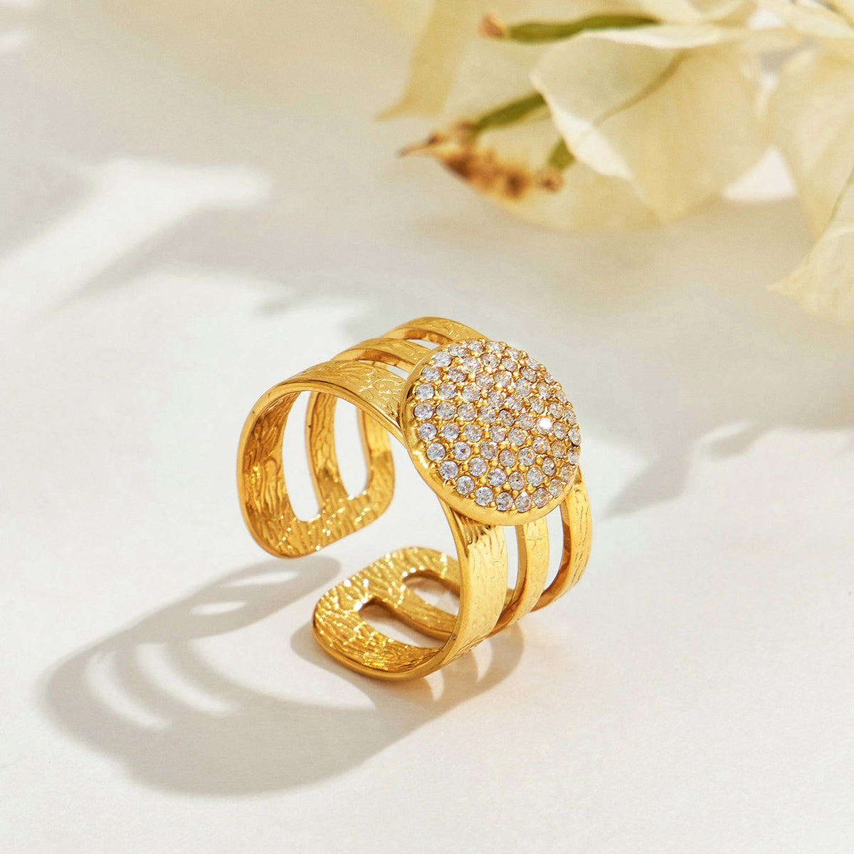 Angled view of the A421 gold-tone stainless steel circle ring showing its clear stone-covered face and open band