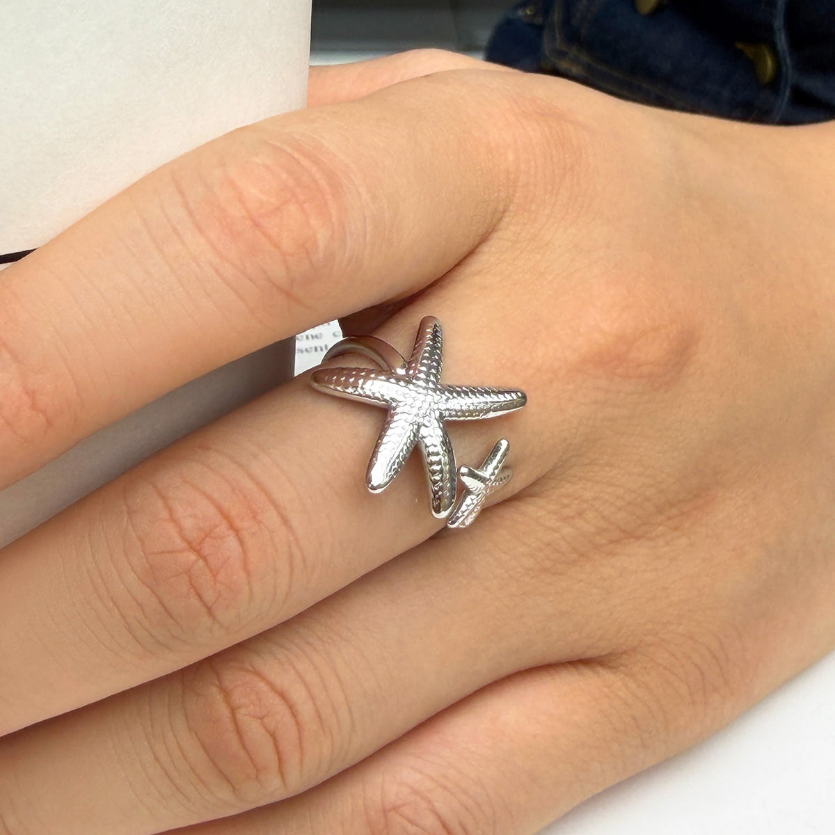 Silver-tone stainless steel starfish open ring worn on a finger, featuring two sculpted sea star details