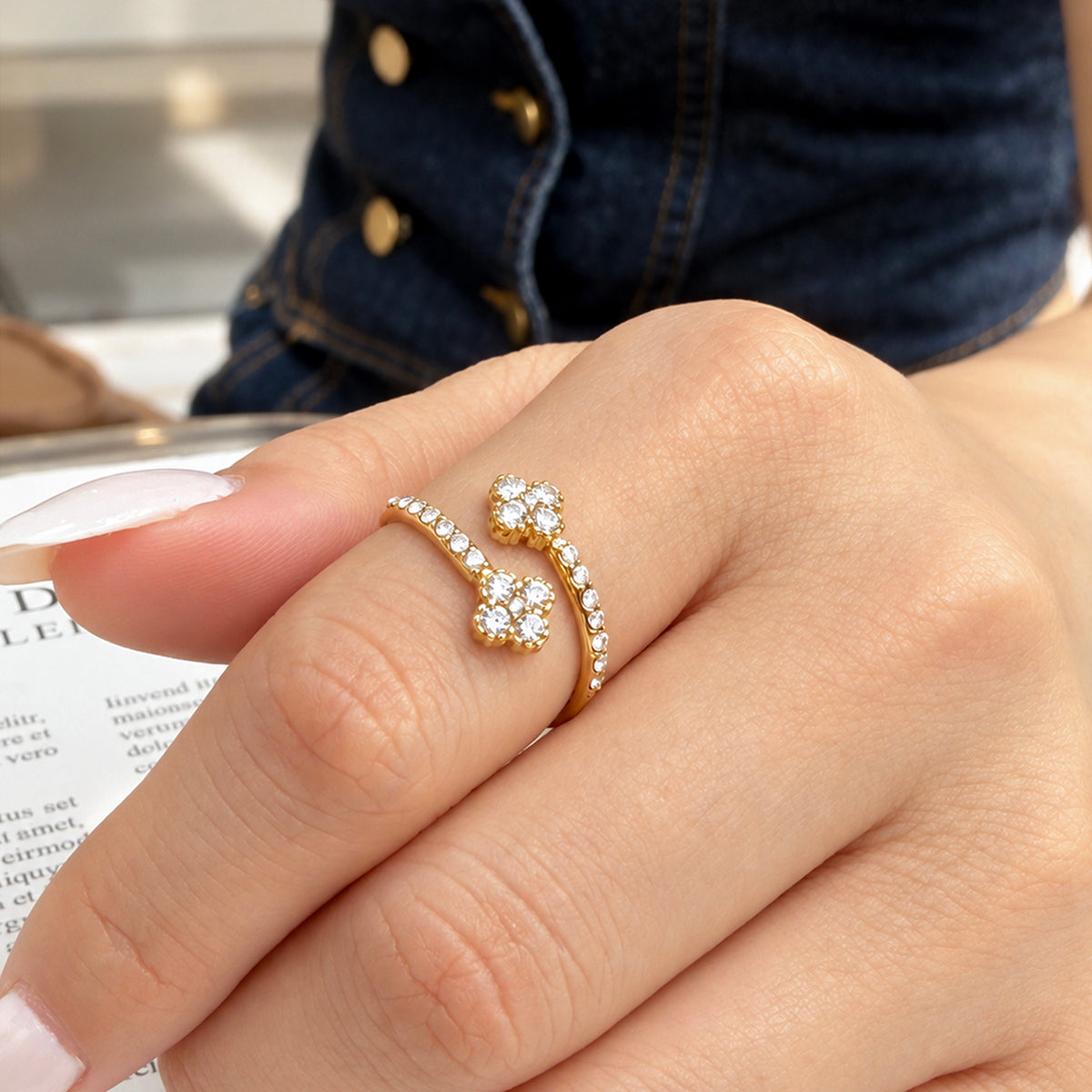 A446 gold-tone stainless steel double-flower open ring worn on a finger, with clear cubic zirconia along the band