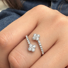 A446 steel-tone stainless steel open ring worn on a finger, showing two four-petal flowers and clear stone accents