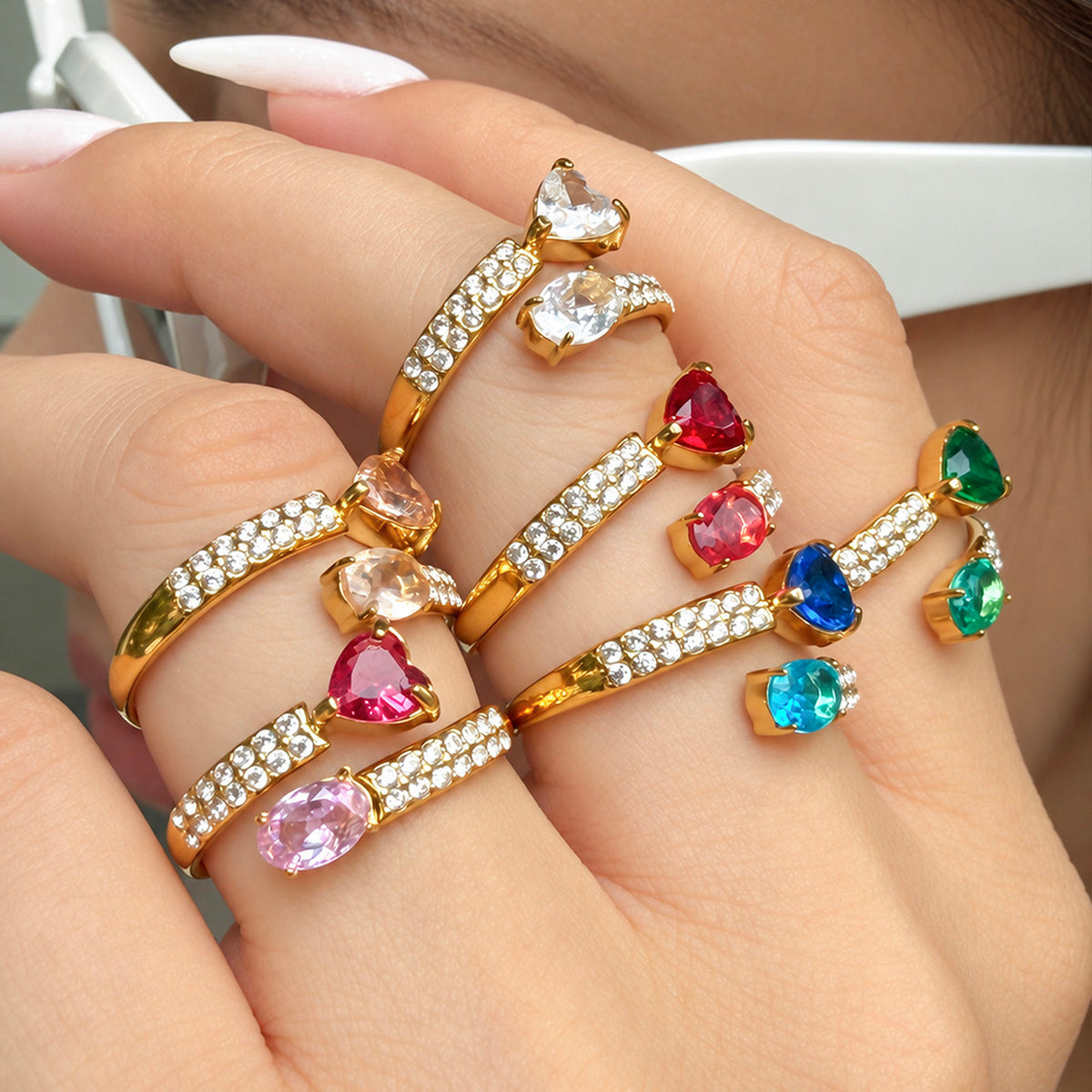 Gold-tone stainless steel heart and oval cubic zirconia rings styled together across a hand