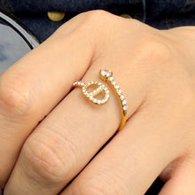 A671 gold-tone stainless steel open ring worn on a finger, showing a vertical oval outline with a horizontal center bar