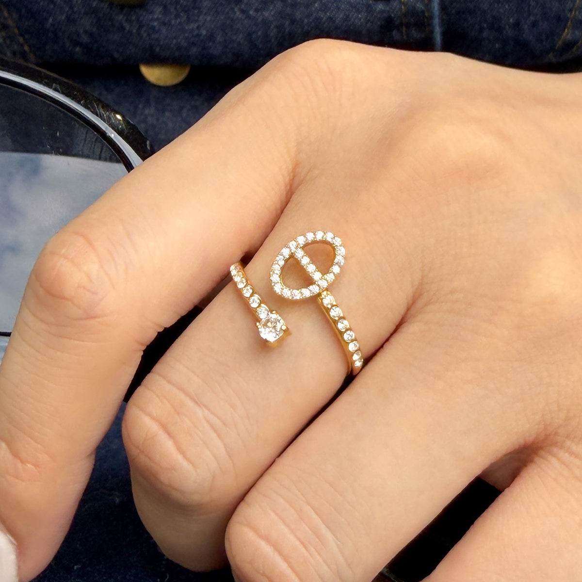 A714 gold-tone stainless steel open ring worn on a finger, showing a horizontal oval outline with a vertical center bar