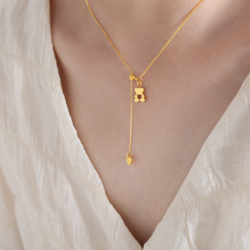 Close-up of a model wearing an adjustable teddy bear necklace with a small heart charm