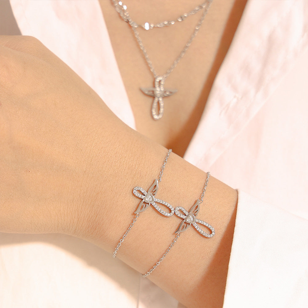 Silver tone angel wing CZ bracelet set worn on wrist, stainless steel waterproof jewelry lifestyle photo.