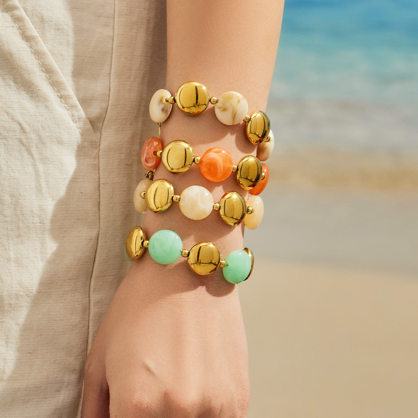 Beach-style close-up of colorful resin bead bracelets stacked on the wrist for a summer jewelry look.