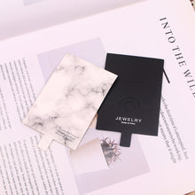 Black and white jewelry display cards with marble-style card options on a light background