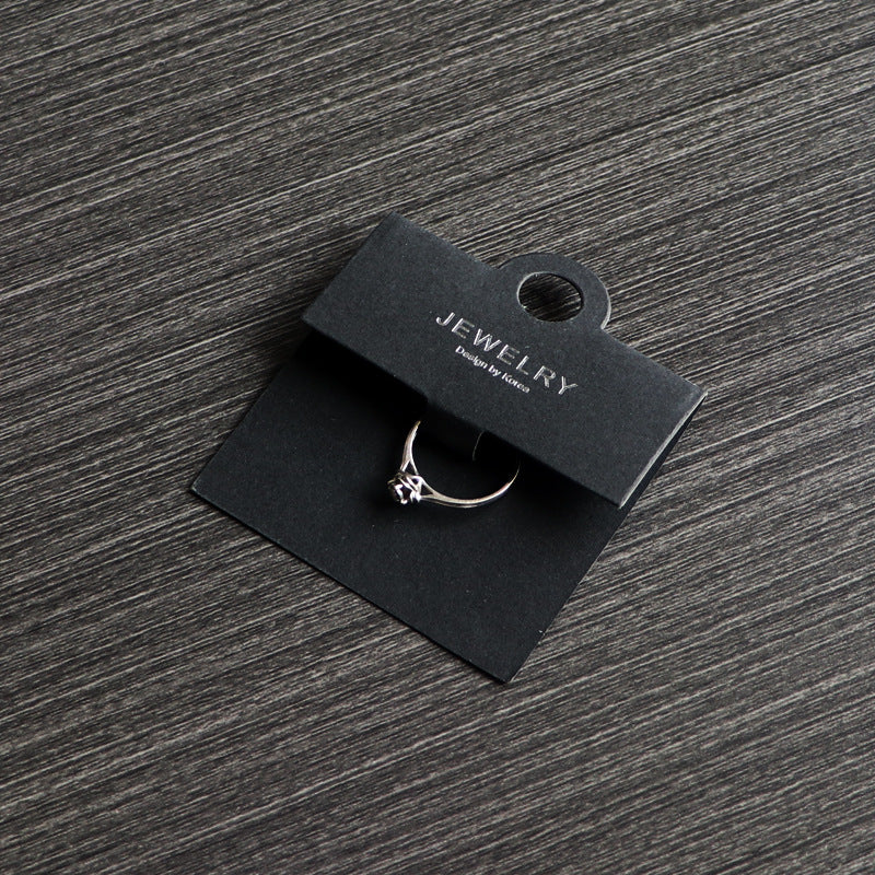 Black ring display card holding a ring on a dark tabletop
