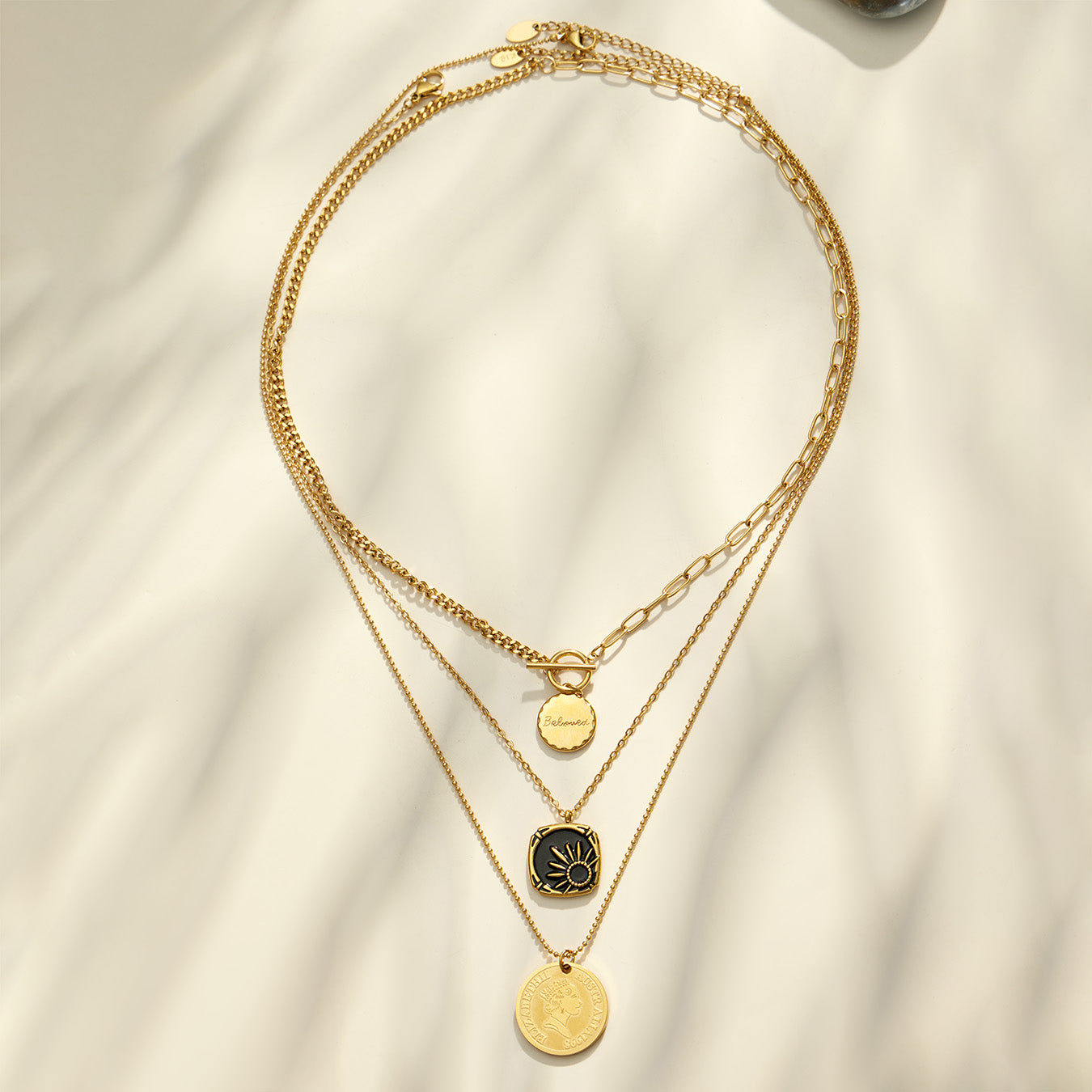 Black enamel sun and round medallion necklaces arranged in a circular layered flat lay