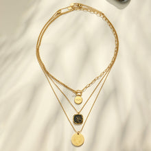 Black enamel sun and round medallion necklaces arranged in a circular layered flat lay