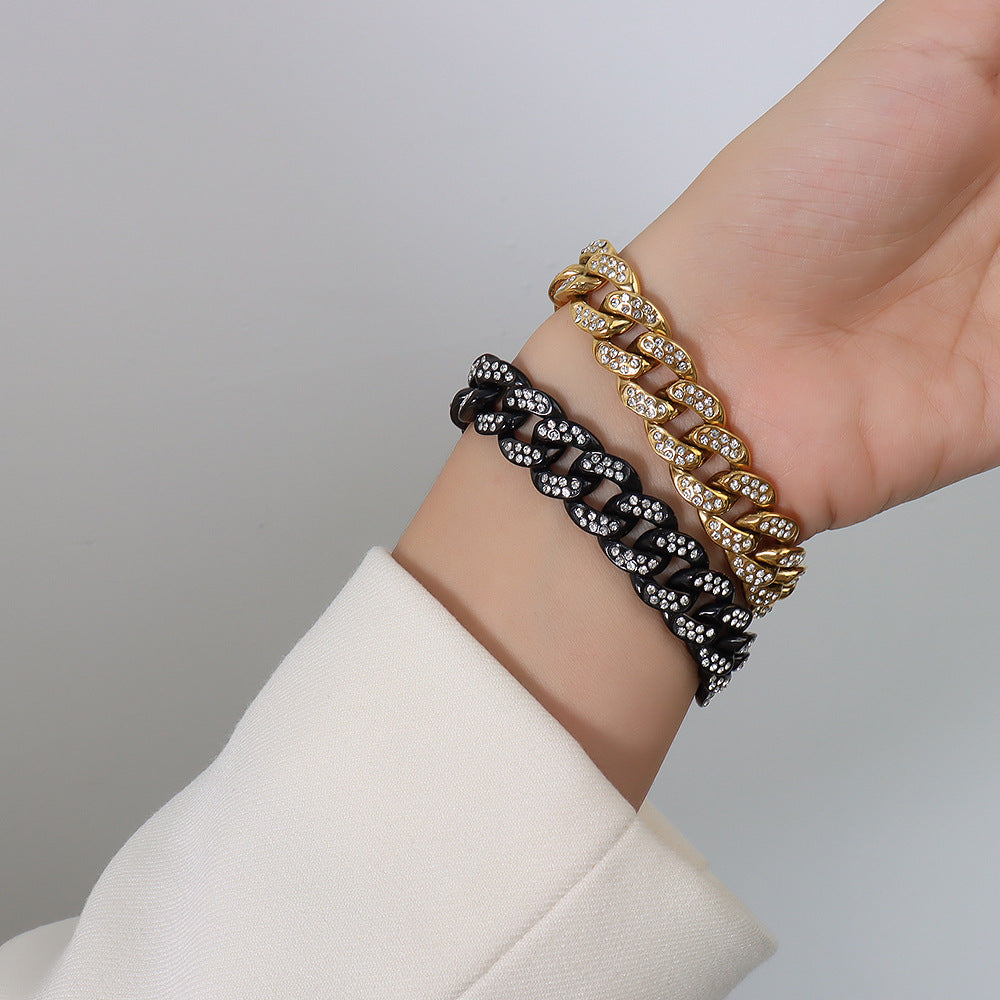 Model wearing black and gold chunky Cuban link bracelets with clear cubic zirconia