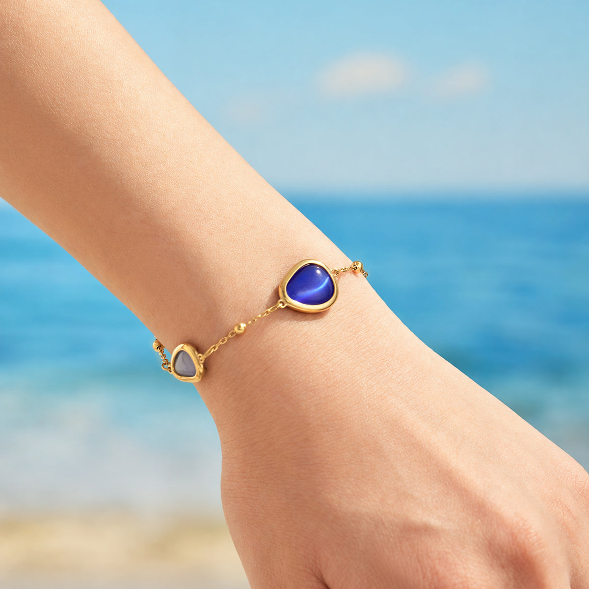 Gold-tone bracelet with blue cat eye stone accents worn on wrist